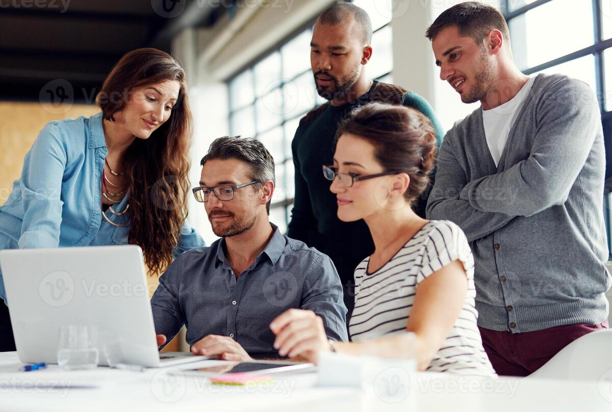 Small IT support team collaborating around a laptop in a modern office